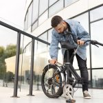 young man using folding bike city